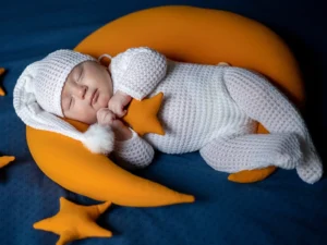 نوزاد خوابیده در کنار عروسکهای ستاره و ماه